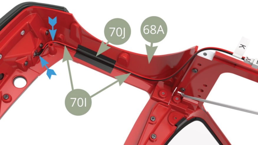 Die linke Seite 70I (Scheinwerferkabel K) mit 70J Klebeband an 68A (vorderer Hilfsrahmen) befestigen. Beachten Sie, dass das Kabel gebogen wird, wie die blauen Pfeile zeigen.