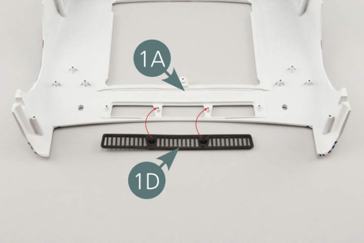 Positionner la grille d’aération 1D sur la carrosserie avant 1A et la fixer avec deux vis QM.