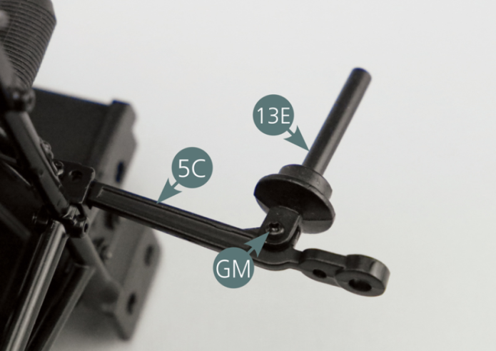 Coloque o pino do pistão da suspensão (13E) no braço inferior esquerdo da suspensão (5C) e fixe-o através do orifício maior com um parafuso GM.