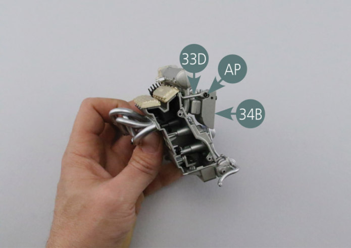 Das Innenteil des Turboladers (34B) auf dem Turbokrümmer (33E) positionieren und mit zwei AP-Schrauben befestigen. 