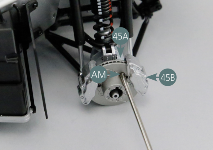 Positionner le second étrier de frein 45B sur le moyeu arrière gauche 45A.Insérer une vis AM à travers le disque de frein et la visser dans l’un des deux points de fixation de l’étrier 45B. Faire tourner le disque de frein jusqu’à trouver l’autre point de fixation de l’étrier, puis insérer une autre vis AM pour fixer l’étrier 45B sur le moyeu arrière gauche 45A.