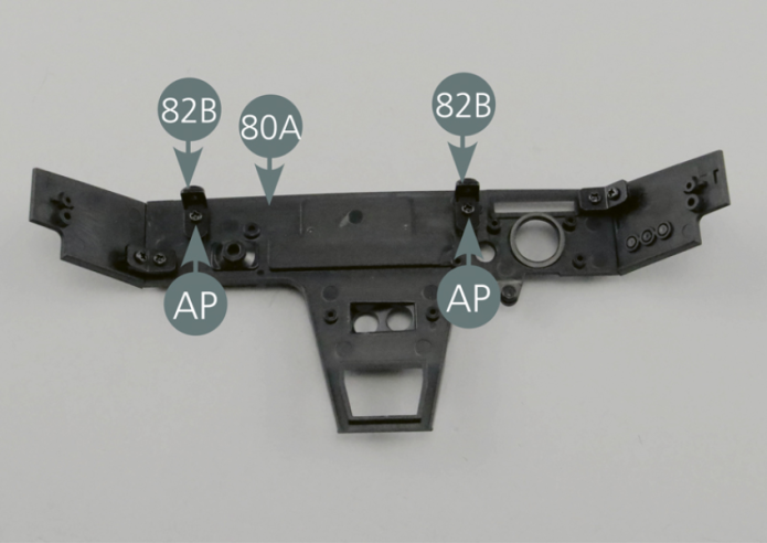 Maintenez le panneau du tableau de bord 80A avec la face interne tournée vers le haut. Positionnez les deux attaches 82B près du bord supérieur comme indiqué sur la photo et les fixez avec deux vis AP.