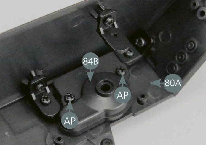 Posiciona la tapa trasera del indicador (84B) en el panel del salpicadero y asegúrela con dos tornillos AP. Verifica el montaje final observando la cara frontal del panel del salpicadero.