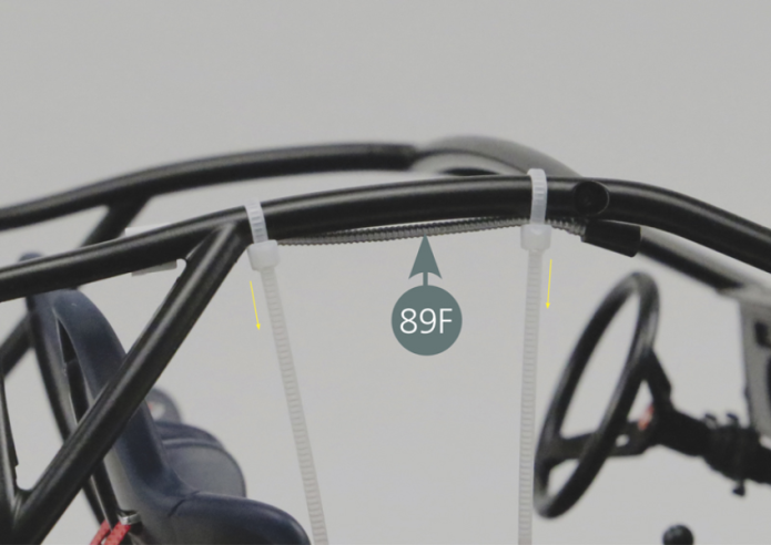 Place the two clamps (89H) on the right roll bar cage (89B) – do not tighten them. Position the passenger’s reading light (89F) as shown and tighten the two clamps. Then cut the excess lengths of the clamps (89H) with a scissor.