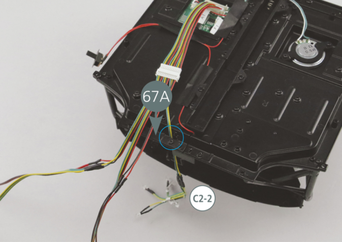 Faire passer les LED C2-2, une à la fois, à travers le trou du plancher gauche du cockpit 67A indiqué par le cercle bleu.Insérer les LED dans les trous prévus sur les panneaux du tableau de bord 80A, 84B et 85D, comme indiqué par les cercles bleus.Retourner le châssis et fixer les câbles avec les deux rubans adhésifs 92F.