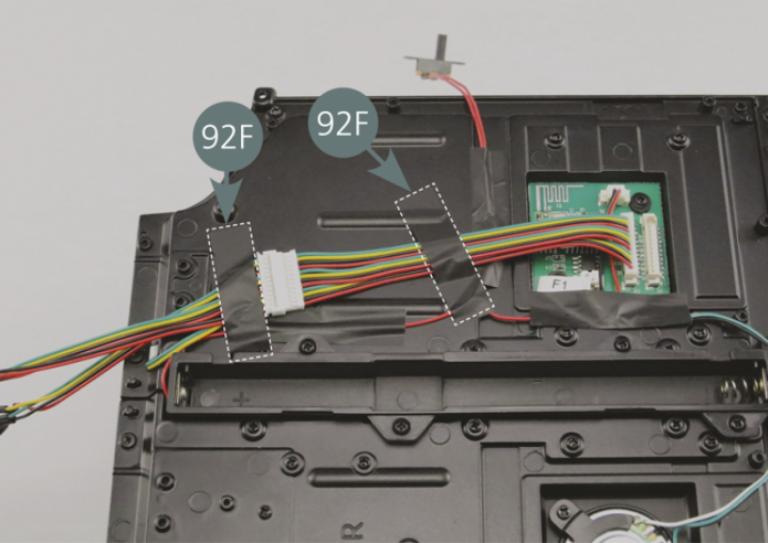 Pass the C2-2 LEDs, one at a time, through the openings in the left floor panel (67A) see blue circle. Insert the LEDs into the openings provided on the dashboard panels (80A, 84B and 85D), see blue circles. Turn the chassis over and secure the cables with the two adhesive tapes (92F).