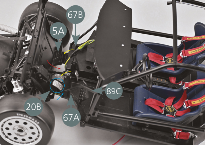 Prendre l’ensemble du châssis avant réalisé à l’étape 86 et l’aligner sur l’ensemble siège-plancher.Basculer le cadre inférieur 5A (comme indiqué par la flèche rouge) et disposer les planchers gauche 67A et droit 67B au-dessus (flèches jaunes). Veiller à ce que la pédale d’embrayage 20B se trouve bien devant le support de l’arceau de sécurité avant gauche 89C, comme indiqué par le cercle et la flèche bleus.