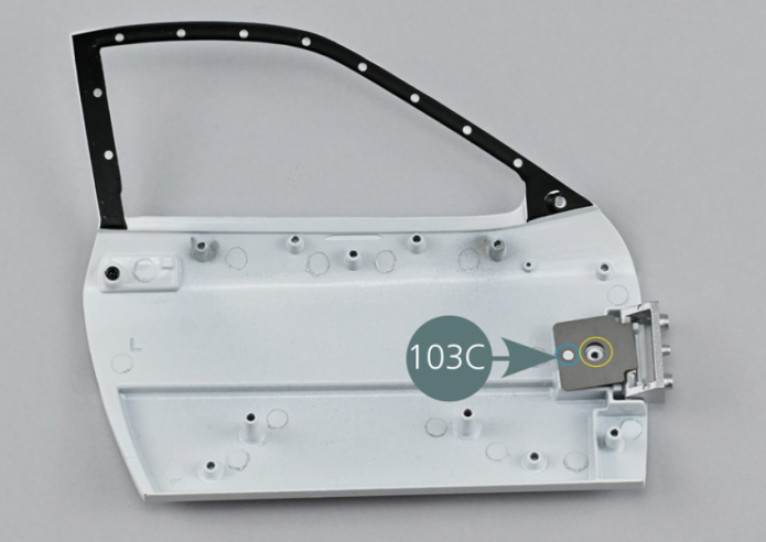 Posiciona la bisagra de puerta (103B) sobre la cara interior de la puerta (103A). Comprueba la correcta orientación de la bisagra (103B). 