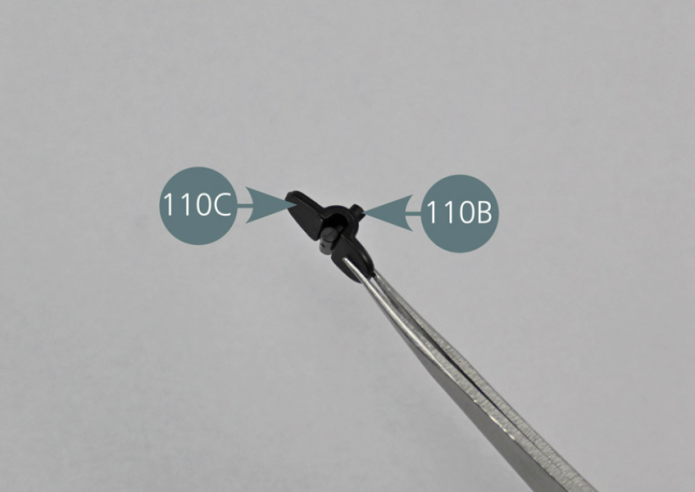 Place the mirror (110A), the joint (110B) and the support (110C) on the work surface. Insert the pin of the joint (110B) into the opening located at the base of the mirror support (110C), as shown in the photos.