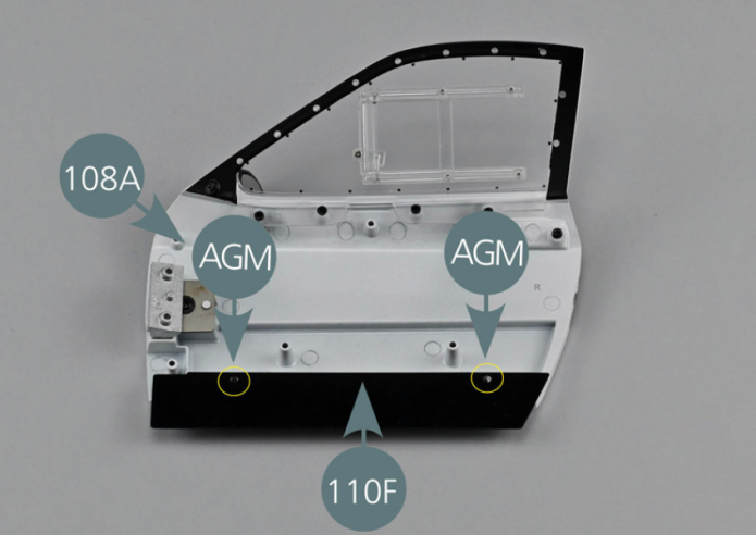 Positionner la protection 110F sur la base de la portière 108A, côté intérieur. Aligner les deux trous de la protection 110 F avec les deux supports de la portière 108A. Fixer la protection de bas de portière 110F avec deux vis AGM (cercles jaunes).