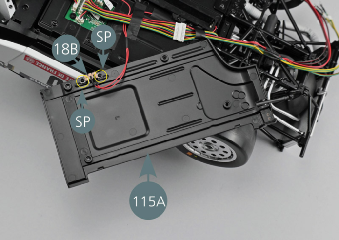 Attach the switch of the battery compartment (18B) to the left lower chassis panel (115A) with two SP screws (yellow circles). Make sure that the connections are oriented towards the inside of the bottom and that the two soldered contacts are towards the right. Turn the left lower chassis panel (115A) over and place it temporarily on the chassis base.