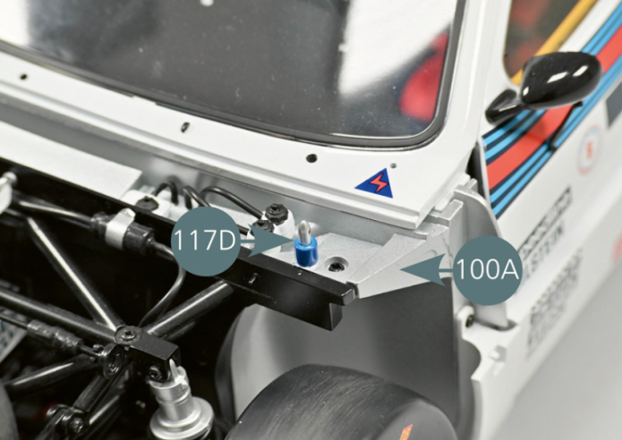 Retourner à nouveau le véhicule et remplacer les deux supports de goupille de capot avant 100B situés de part et d’autre de la cloison d’habitacle avant 100A par les supports de goupille de capot avant 117D.Réinsérer ensuite dans leurs logements les vis AM retirées précédemment.