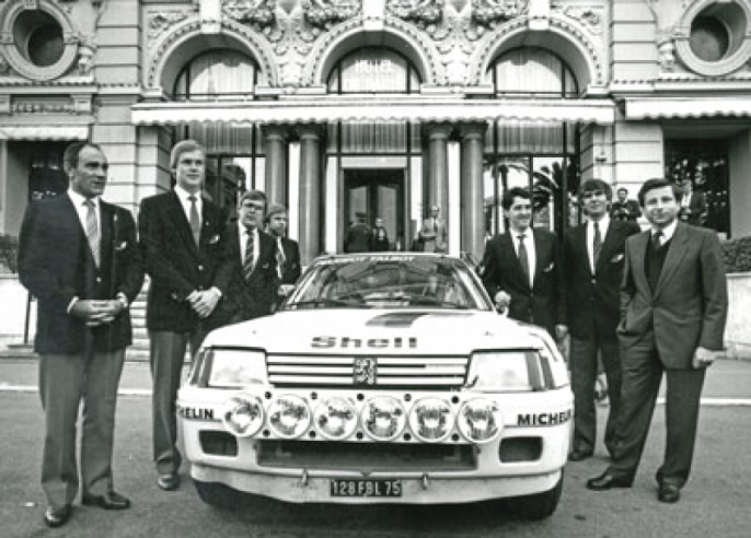 L’équipe Peugeot Talbot Sport autour de la 205 Turbo 16 lors de la présentation du Monte-Carlo de 1985 où Vatanen et Harryman (à sa droite) triompheront.© IXO Collections SAS - Tous droits réservés. Crédits photo © Peugeot