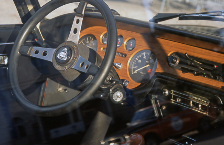 L’habitacle du coupé est lumineux et soigné, avec la planche de bord façon bois précieux et le volant en cuir à trois branches de type Rallye.© IXO Collections SAS - Tous droits réservés. Crédits photo © © Lancia D.R.