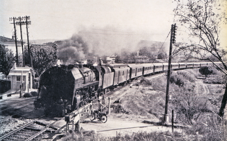 Une « R » en tête d’un interminable et lourd train de voyageurs régional sur la Côte d’Azur en 1963. Le propriétaire de la « Mob », version un peu sport avec sa selle banane double place, peste et perd du temps sur le passage à niveau. La « R » prend son temps…  © IXO Collections SAS - Tous droits réservés. Crédits photo © photographie Yves Broncard