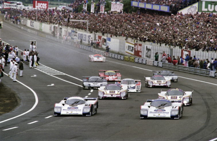 Photo prise peu après le départ des 24 Heures du Mans 1987 dominées par Porsche, qui remporte les deux premières places absolues avec deux 962C (ici en tête). Dans cette édition, la 961 abandonne sur accident après une belle remontée. © IXO Collections SAS - Tous droits réservés. 